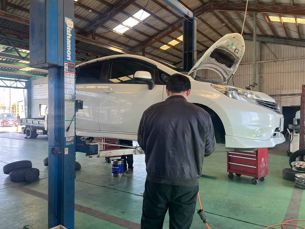 リフトで上げている自動車 作業しているスタッフ