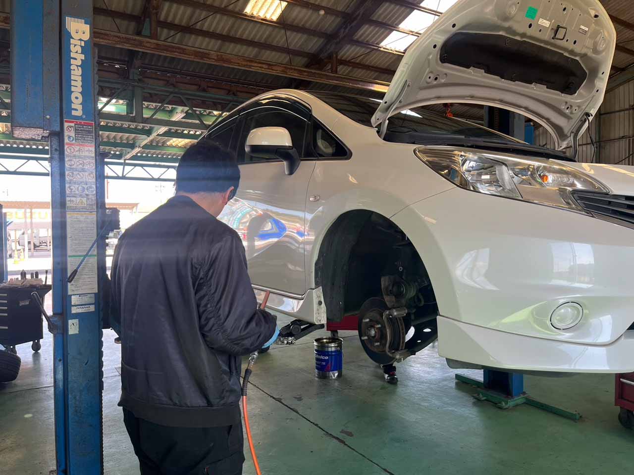 リフトで上げている自動車 作業しているスタッフ